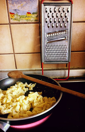 Stir-frying spaetzle, German soft egg noodles, in the kitchen on the cooking plateの写真素材