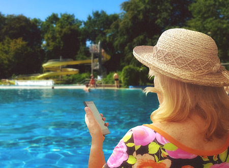 blonde woman looking at her cellphone in holidayの写真素材