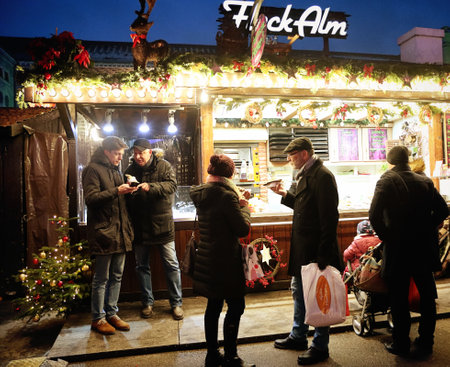Munich, Germany - festive atmosphere at Residenz Kaiserhof Christmas market illuminated at night, crowded with tourists and residents, here a kiosk selling foodのeditorial素材