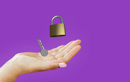 image symbolizing data protection and privacy: lock and key in your hand, on purple-violet backgroundの写真素材