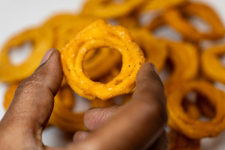 This image is about in hand Holding Butter Murukku in white background Stock Photoの写真素材