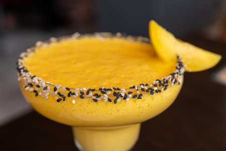 This image is about Mango shake filled in glass topping of real mango in side close-up shot and in corner paste white and black seedsの写真素材