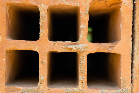 A close-up of a red brick wall with an old, rusted iron door handle sticking out from a small hole.の写真素材