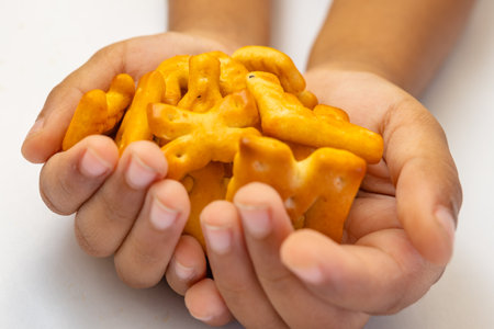 This image is about Kid holding Abc biscuits alphabet yellow background. stock photo XYZの写真素材