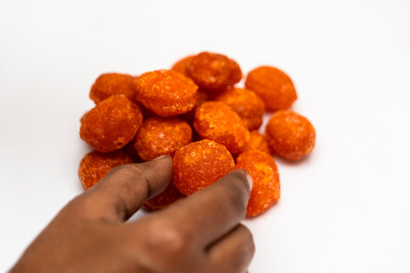 A close-up of a hand holding a piece of Indian traditional honey candy, thaen mittai.の写真素材