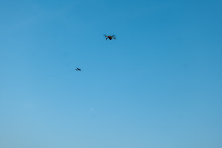 aerial spectacle as a drone and an airplane gracefully soar through the vast expanse of the blue sky.の写真素材