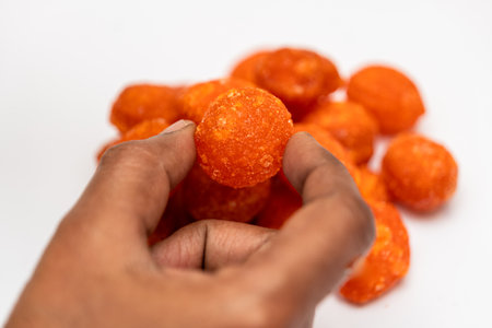 A close-up of a hand holding a piece of thaen mittai, a traditional Indian honey candy.の写真素材