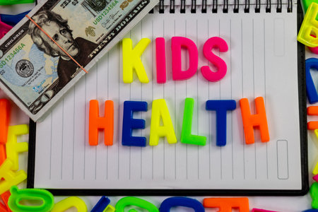 A close-up of colorful letter magnets spelling out Kids health on a plain piece of dairy, with a...