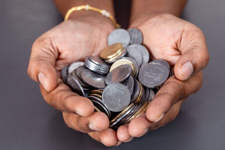 A close-up of a hand holding a large number of Indian coins.