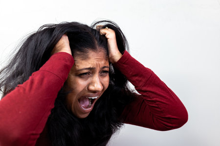 A close-up of a woman's face, her eyes closed and her mouth open in a shoutの写真素材