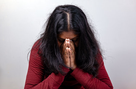 A sad woman is covering her nose with her hands. She looks unhappy and disgustedの写真素材