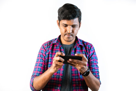 A young man in his twenties is sitting on a couch, holding a mobile phone in his handsの写真素材