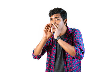 A young man in his 20s is making a long distance call, waving his hand excitedly. He is standing in...