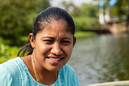 A sun-kissed woman, eyes sparkling with freedom, navigates her small sailboat acrossの写真素材
