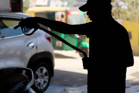 Silhouette of a man refueling a car at a water washの写真素材