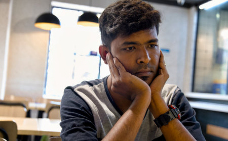 Portrait of a young man sitting in a coffee shop and looking at cameraの写真素材