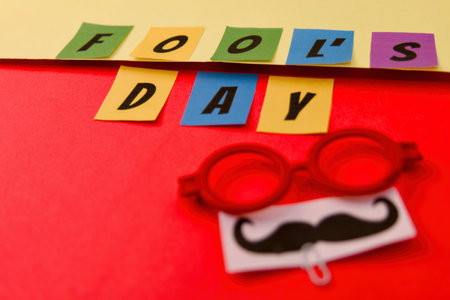 fools day concept with letters and glasses on a red background.の写真素材