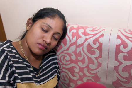 indian women sleeping and tearing on sofa at home, lifestyle people conceptの写真素材