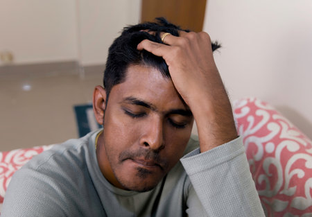 Young man suffering from headache at home. Selective focus on headの写真素材