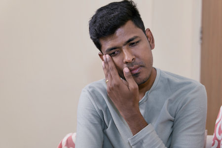 young indian man suffering from toothache and tooth decay at home