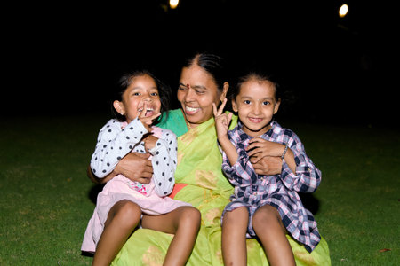 indian family sitting on the grass in the garden at night.