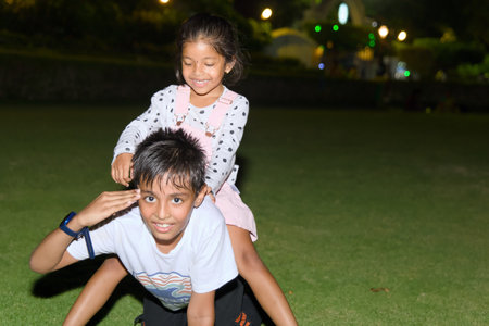 Indian Brother and sister playing together in the park at night.の写真素材