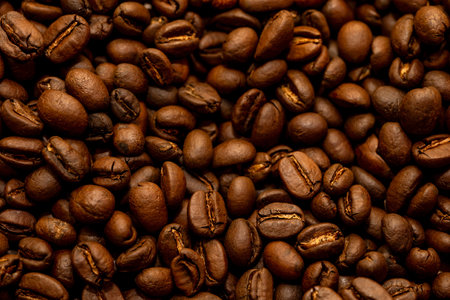 Close-up view of glossy roasted coffee beans, exuding rich aromas. Perfect for coffee enthusiasts...