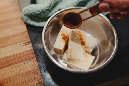 Hands preparing a delicious paneer dish on a wooden surface.の写真素材