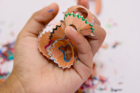 A hand holds a pile of colorful pencil shavings, likely just removed from a pencil sharpener.の写真素材