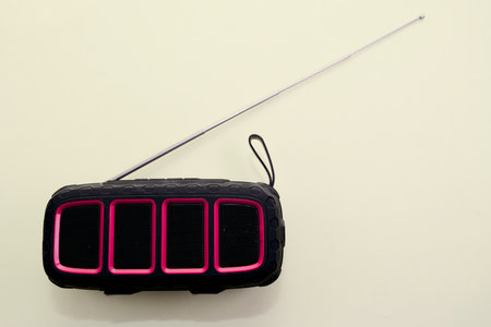 A compact black and pink portable radio with an extended antenna placed on a light-colored surface.の写真素材