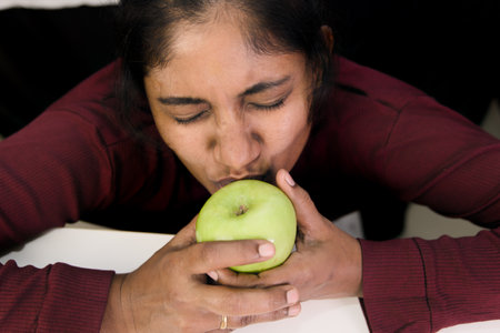 A woman affectionately embraces a green apple, emphasizing freshness and healthy eating.の写真素材