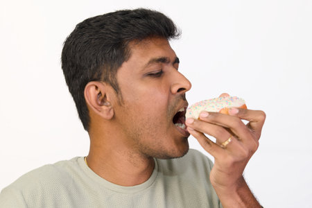 Young man indulging in a delicious donut with a joyful expression.