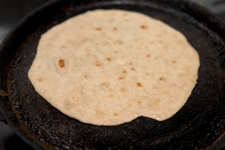A traditional Indian flatbread, chapati, sizzles on a hot griddle. The aroma of home-cooked goodness...