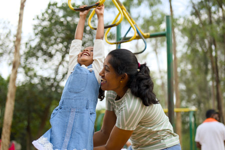 Mom cheers as her daughter reaches new heights on the monkey bars.