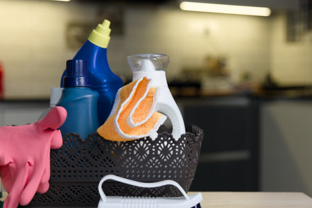 A collection of essential household cleaning supplies, including detergents and sponges, displayed on a kitchen counter, showcasing cleanliness and organization.の写真素材