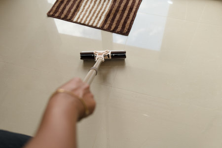 A person mops a tiled floor, focusing on cleanliness and hygiene in a home setting. The image...