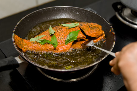 Aromatic spiced fish frying to perfection in hot oil, ready to tantalize taste buds.の写真素材