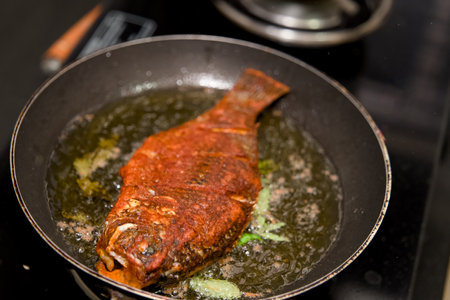 Flavorful red snapper frying to perfection in oil, garnished with herbs.  A delicious seafood meal...