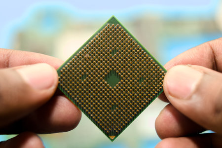 Fingers carefully hold a computer processing unit against a blurred blue background.の写真素材