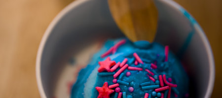 A tempting scoop of blue ice cream with colorful sprinkles and a wooden spoon, ready for a delightful summer treat.の写真素材