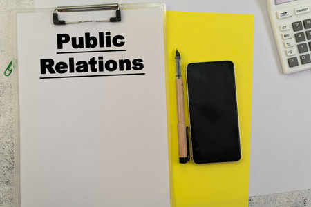 Plan your PR campaign.  Clipboard, phone, pen, calculator, and yellow accent ready for your message.の写真素材
