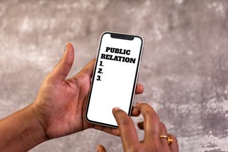 Hands holding a smartphone with Public Relation and a numbered list displayed, suggesting PR...