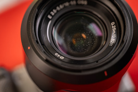 Close-up of a dusty camera lens against a vibrant red backdrop. A reminder of the importance of keeping your gear clean for optimal image quality.の写真素材