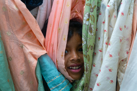 Playful peekaboo among colorful fabrics. A young girl's joyful smile shines through.