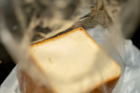 Freshly baked bread slice, partially visible through clear plastic packaging. Ready for a delicious sandwich or toast.の写真素材