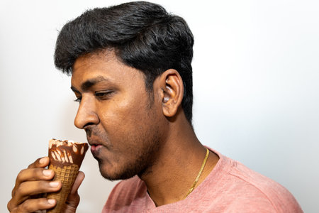 Young man enjoying a delicious chocolate ice cream cone. Perfect for food, lifestyle, and summer themes.の写真素材