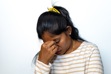 Young woman suffering from a headache, sinus pain, or migraine. Isolated on white.の写真素材