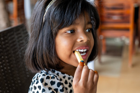 Cute young girl enjoying food at a restaurant.の写真素材