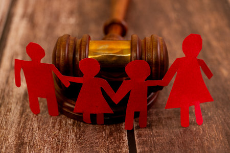 Red paper family chain in front of a gavel. Child custody, divorce, and adoption legal concepts.の写真素材