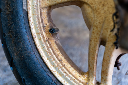 Close-up of a weathered, rusty wheel with a tire valve stem. Time, elements, and neglect have taken their toll.の写真素材